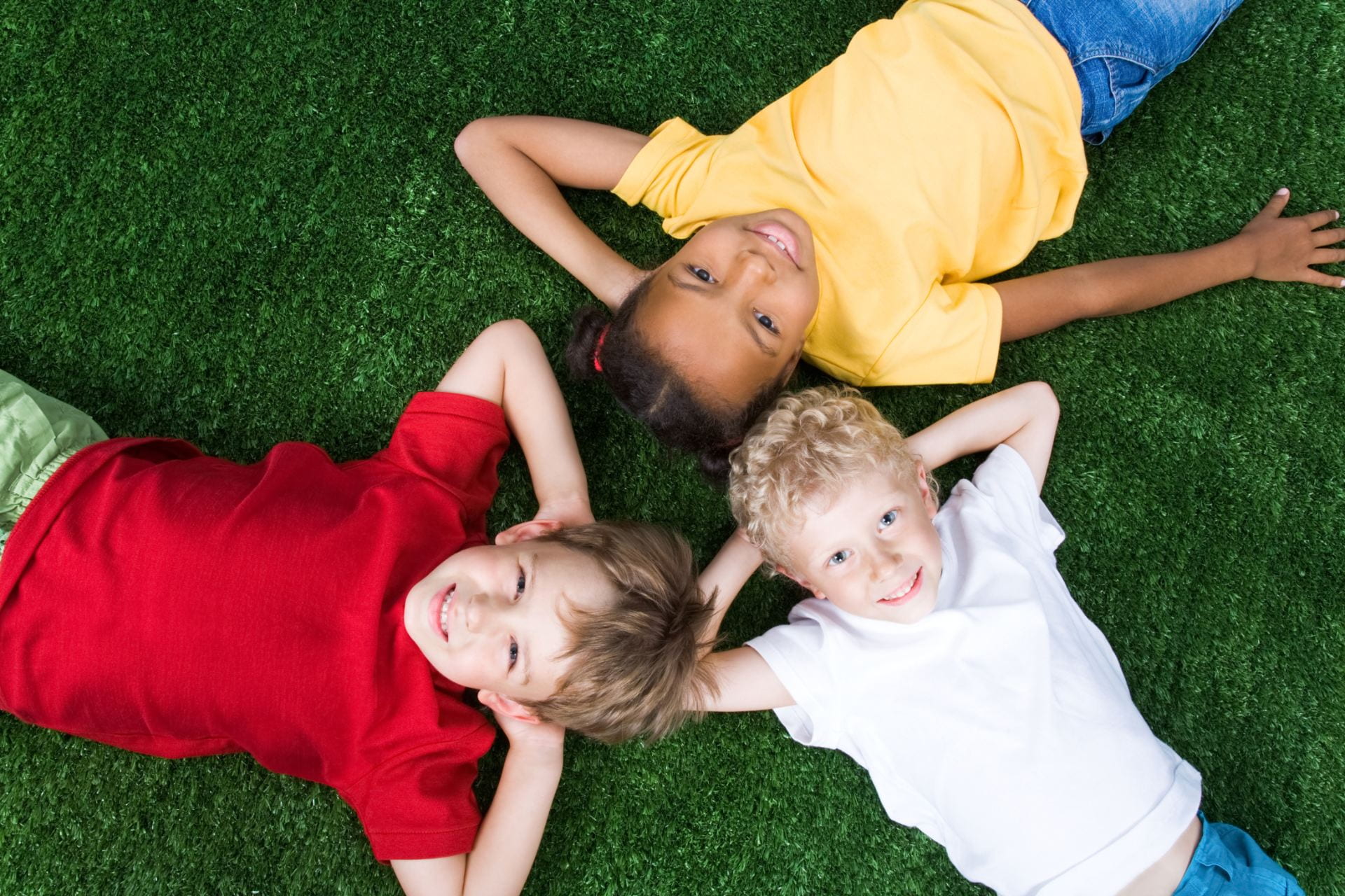 Three children lying on the grass.