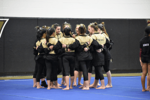 The whole FHS Gymnastics team huddles and chants together before the meet starts
